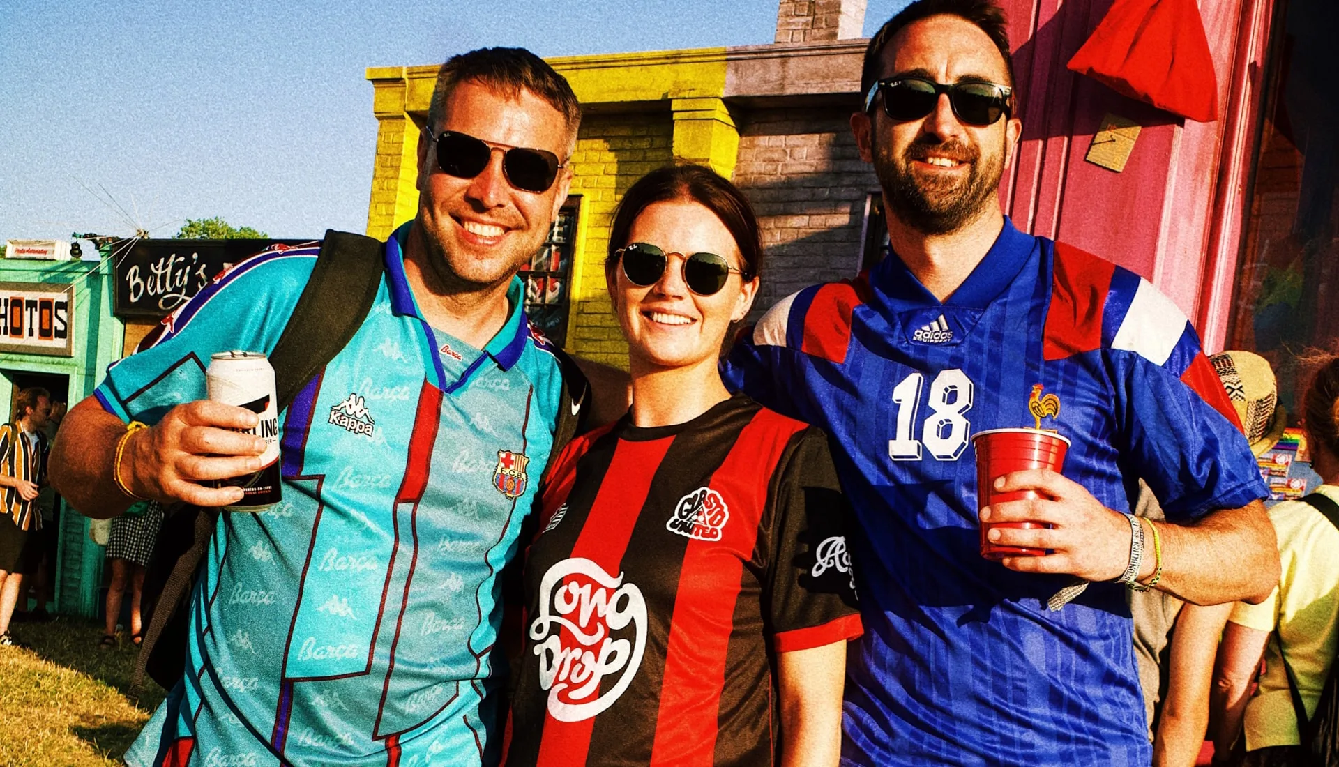 Three friends at a festival wearing vintage Barcelona, Crystal Palace and France 1998 jerseys